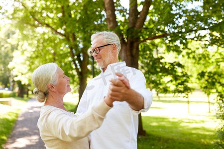 老人舞蹈摄影照片_老年、关系和人概念-愉快的资深夫妇跳舞华尔兹在夏天城市公园。快乐的高级夫妇跳舞在夏天城市公园