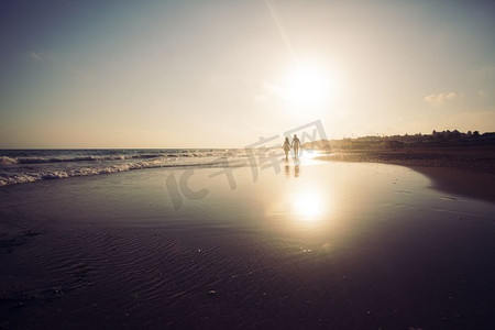 洛阳剪影摄影照片_沿着沙滩和享受日落走的爱的夫妇剪影.年轻的浪漫夫妇在海岸线