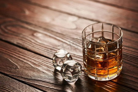 一杯威士忌加冰块，放在带有复制空间的乡村木桌上