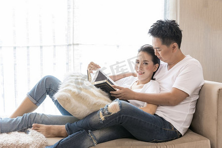 读书分享摄影照片_年轻夫妇在当代住宅客厅里一起读书，分享生活方式理念