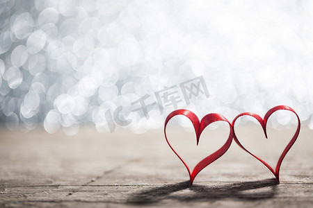 丝带光摄影照片_两个心形的丝带。两个红色丝带心脏在木backround，情人节概念