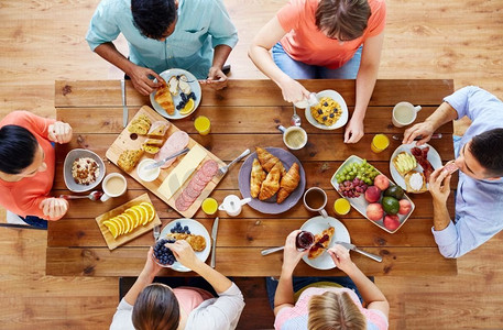 食物、吃和家庭概念-吃早餐和坐在桌的一群人。一群人在餐桌上吃早餐