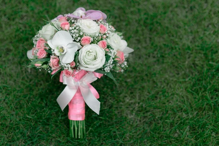 草地上的婚礼花束，有玫瑰、兰花和丝带