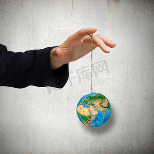 自然与人类近摄人的手拿着地球行星在绳子上。这张图片的元素是由美国宇航局提供的