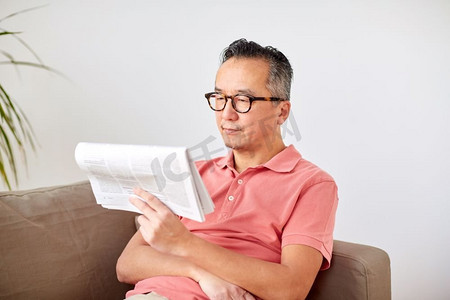 休闲、信息、人与大众传媒理念--戴着眼镜在家看报的快乐人。戴眼镜的快乐男人在家看报纸