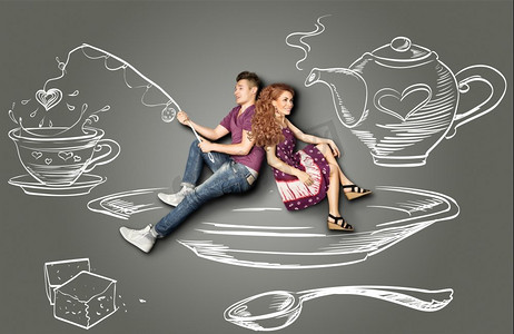 幸福的情人节爱情故事概念：一对浪漫的情侣坐在茶碟上，在茶杯里钓鱼，背景是粉笔画。