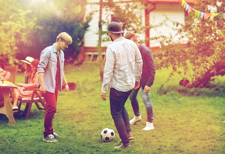 休闲，假期，人和运动的概念-快乐的朋友在夏日游园会上踢足球。快乐的朋友在夏日花园踢足球