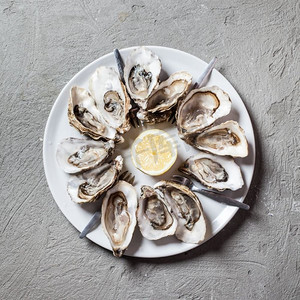 美味的牡蛎配柠檬切片，顶视图中有文字显示。盘子里的牡蛎