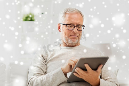 漫天摄影照片_科技、人和生活方式理念--老人在家中带着平板电脑漫天飞雪。家中有平板电脑的老人