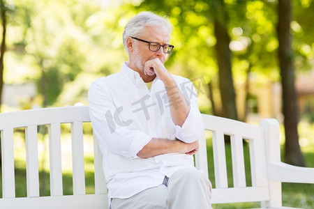 坏老人摄影照片_老年、退休和人的概念--夏季公园里一位深思熟虑的戴眼镜的老人。夏令营体贴的老人