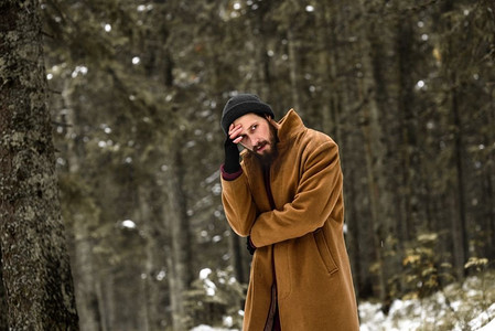 冬天森林里的一个人很冷，穿着棕色外套，戴着手套