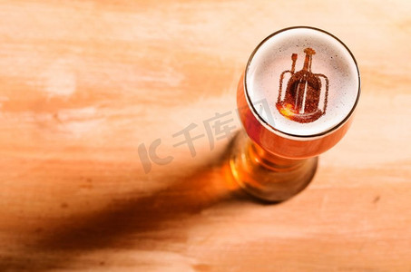 本地精酿啤酒。啤酒厂的剪影在酒吧桌子上的一杯新鲜啤酒中，从高处俯瞰。本地精酿啤酒