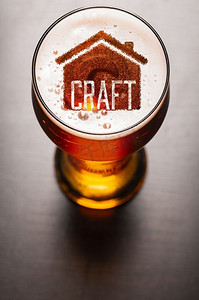 本地精酿啤酒。酒吧桌上一杯新鲜啤酒中的房子剪影，从高处俯瞰。本地精酿啤酒