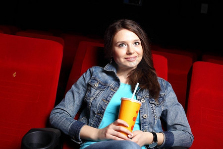 坐在车里看电影摄影照片_年轻女孩坐在电影院里看电影