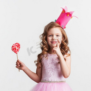 公主粉摄影照片_糖果小公主。美丽的小糖果公主，戴着皇冠，手持大粉心棒棒糖，微笑着