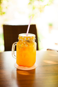 木桌上盛满了新鲜橙汁和鸡尾酒吸管的酒杯。新鲜的橙子之乐