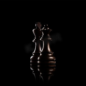 战场人物摄影照片_象棋概念黑木国王和王后，黑暗背景下最有权势的人物站在一起。