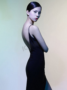 时尚工作室彩色背景下穿着黑色连衣裙的美女肖像。亚洲美女。