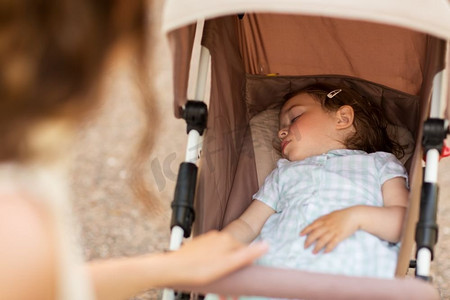 家庭、母性和人的概念-母亲与睡在婴儿车的孩子。母亲与孩子睡在婴儿车