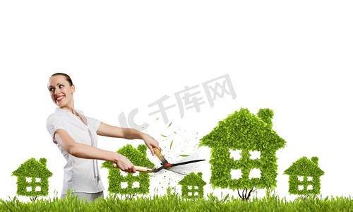 绿化理念。年轻漂亮的女商人修剪房屋形状的草坪