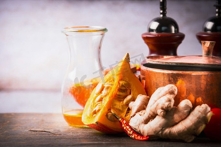 南瓜放在厨房桌子上，有锅、油和生姜。食物背景对秋季烹饪的启发和秘诀