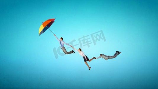 逃离摄影照片_逃离办公室。商务人士撑着伞在天空中飞翔