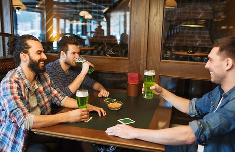 色绿摄影照片_人，休闲和圣帕特里克节的概念-快乐的男性朋友在酒吧或酒吧喝绿啤酒。在酒吧或酒吧喝绿啤酒的男性朋友