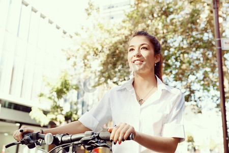 快乐的年轻女自行车手的肖像。快乐的年轻女骑车人在城市里骑行的肖像