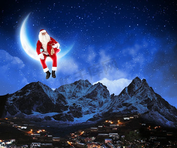 圣诞老人坐在月球上的照片。圣诞老人坐在月球上的照片，下面是城市和山脉