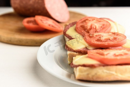 腊肠切片摄影照片_热三明治配融化的奶酪香肠、意大利腊肠和西红柿