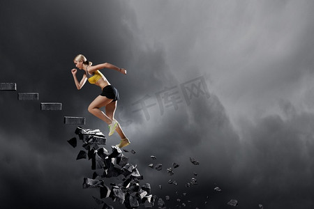 女运动员克服挑战在石头上跑的体育活跃的妇女倒塌梯子