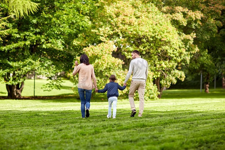 家庭，父母，收养和人的概念-快乐的母亲，父亲和小女孩在夏令营散步。快乐的一家人在夏季公园散步