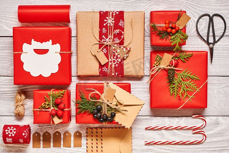 信封糖果摄影照片_创意包装和装饰的圣诞礼物在白色木制背景的盒子里。从上面俯瞰。平躺着。