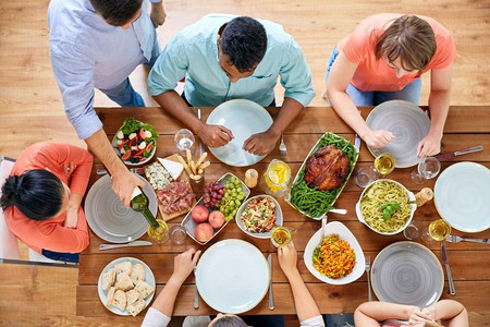 感恩节，吃喝玩乐的概念-一群人在餐桌上吃晚餐，带着食物。一群人带着食物在餐桌上吃饭