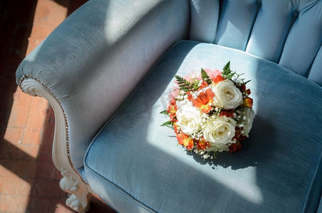 在蓝色天鹅绒柔软的古董椅上的新娘花束