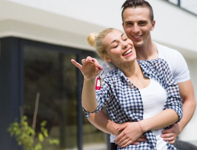 一对幸福的年轻夫妇在他们的新豪华别墅前拥抱