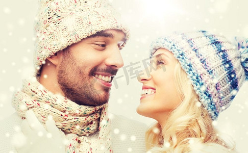冬天，时尚，情侣，圣诞节和人的概念-戴着帽子和围巾微笑的男人和女人拥抱。一对穿着冬衣的微笑情侣拥抱着