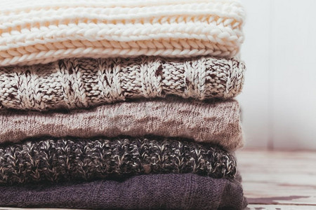 舒适摄影照片_把暖和的针织毛衣堆成白色和灰色。羊毛衫系列
