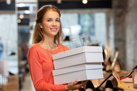销售、购物和人的概念-快乐的年轻女子或商店里拿着鞋盒的店员。商店里拿着鞋盒的女人或店员