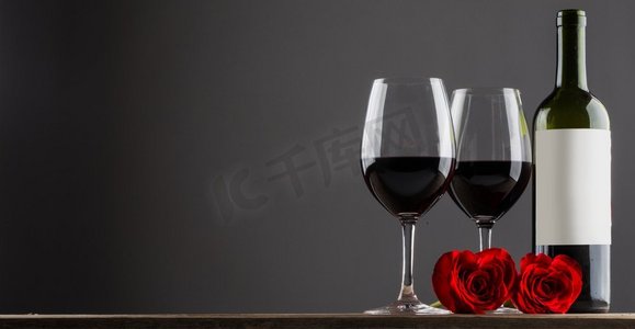 红酒和玫瑰。两杯红酒和心形玫瑰放在木桌上，灰色复印区