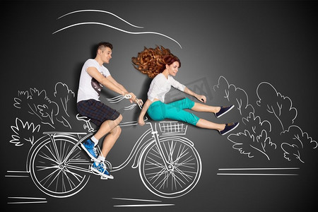 愉快的情人节一对浪漫的夫妇的爱情故事概念反对粉笔画背景。男骑他的女朋友在前面的自行车篮子。