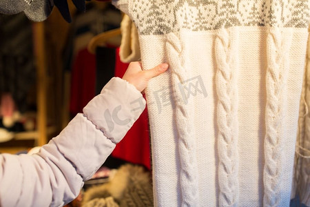针织品与人的概念--女人在圣诞集市买毛衣的特写。一名女子在圣诞集市上购买羊毛衣服