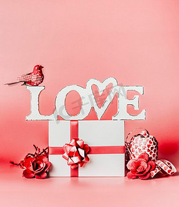 装饰礼物盒摄影照片_情人节浪漫静物构图与文字爱和问候设置：礼品盒，丝带，红色背景，正视装饰。