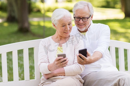 老年、科技和人的概念快乐的老年夫妇在夏季公园拿着智能手机。快乐的高年级夫妇在公园里拿着智能手机