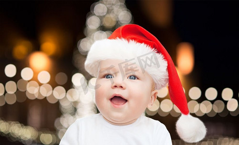 节日和人们的概念-戴着圣诞帽的小男孩在圣诞树上的背景。圣诞节戴着圣诞帽的小男婴