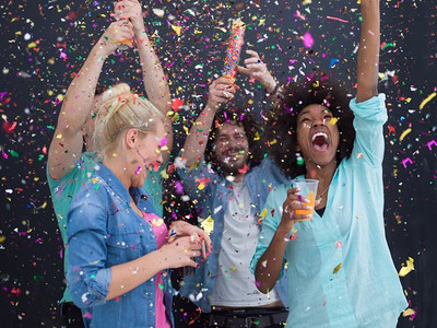 五彩纸屑派对 多民族快乐的年轻人一边跳舞一边庆祝新年前夜,在灰色