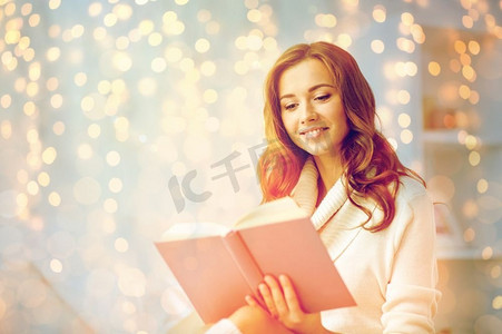 圣诞节、休闲和百姓观念快乐的年轻女子在家中读书。快乐的年轻女子在家看书