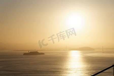 金色城市背景摄影照片_旧金山湾的日出，背景是市中心