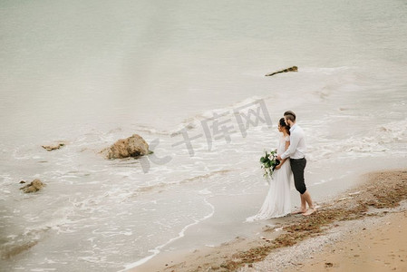 年轻的新人和新娘在沙滩上走在婚礼上