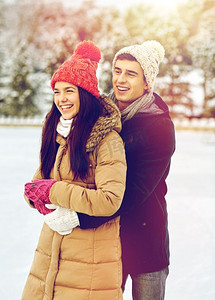 人、冬、爱、闲理念--户外溜冰场上拥抱的幸福情侣。幸福的情侣在户外溜冰场滑冰